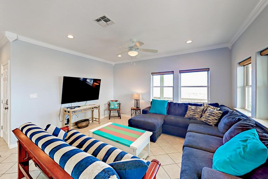 sala de estar con sofá azul y TV en Gulf Breezes & Dune Dreams, en Port Aransas