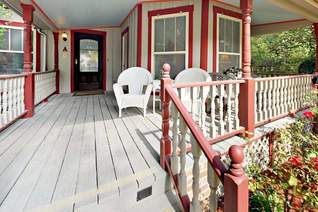 un porche con sillas blancas y una casa roja en Little house on Monroe en Austin
