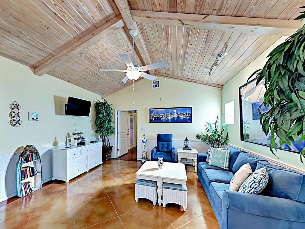 a living room with a blue couch and a ceiling fan at Sail Away at Pirate's Bay Unit 113 in Port Aransas