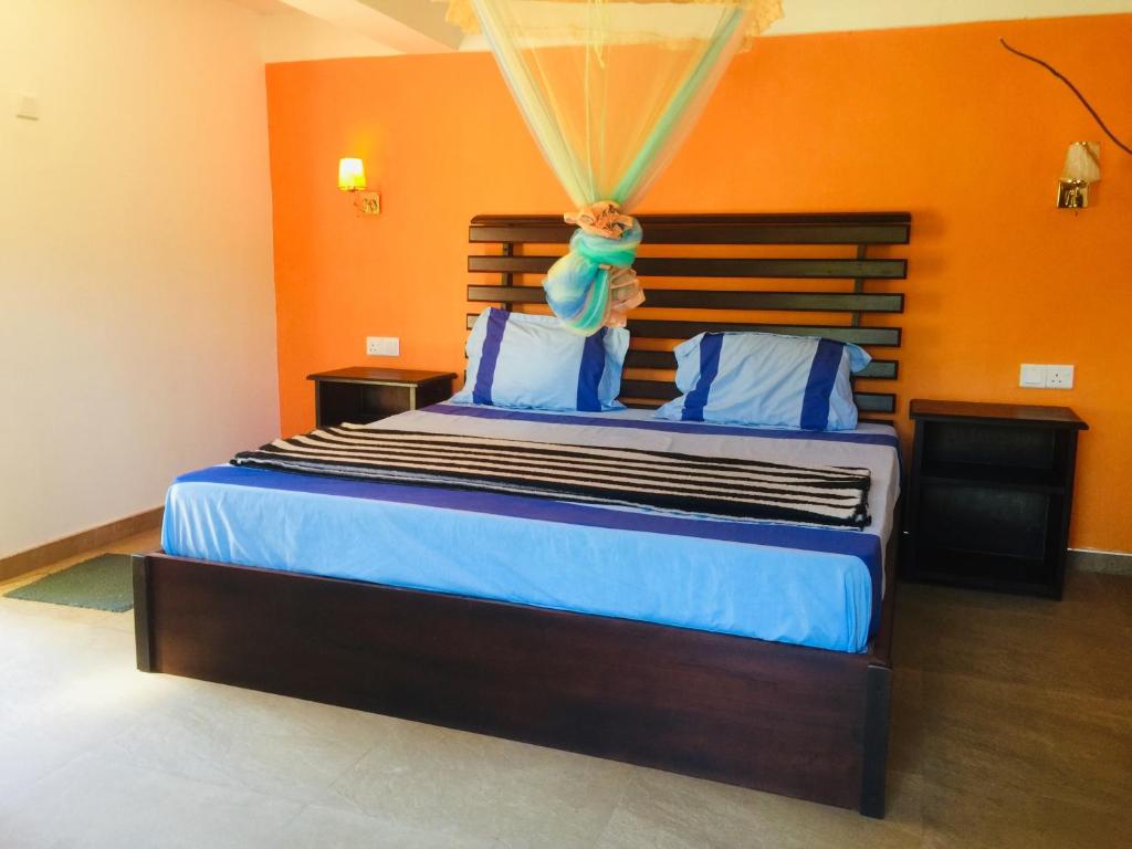 a bedroom with a large bed with an orange wall at orchid villa in Ella