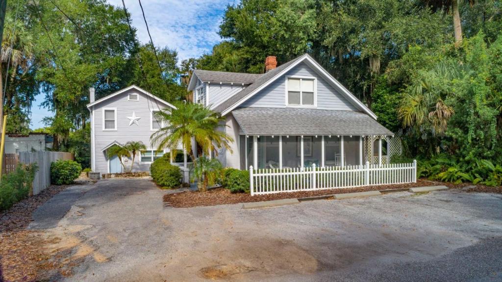 a house with a white fence and a palm tree at Historic Tremain Cottages in Mount Dora