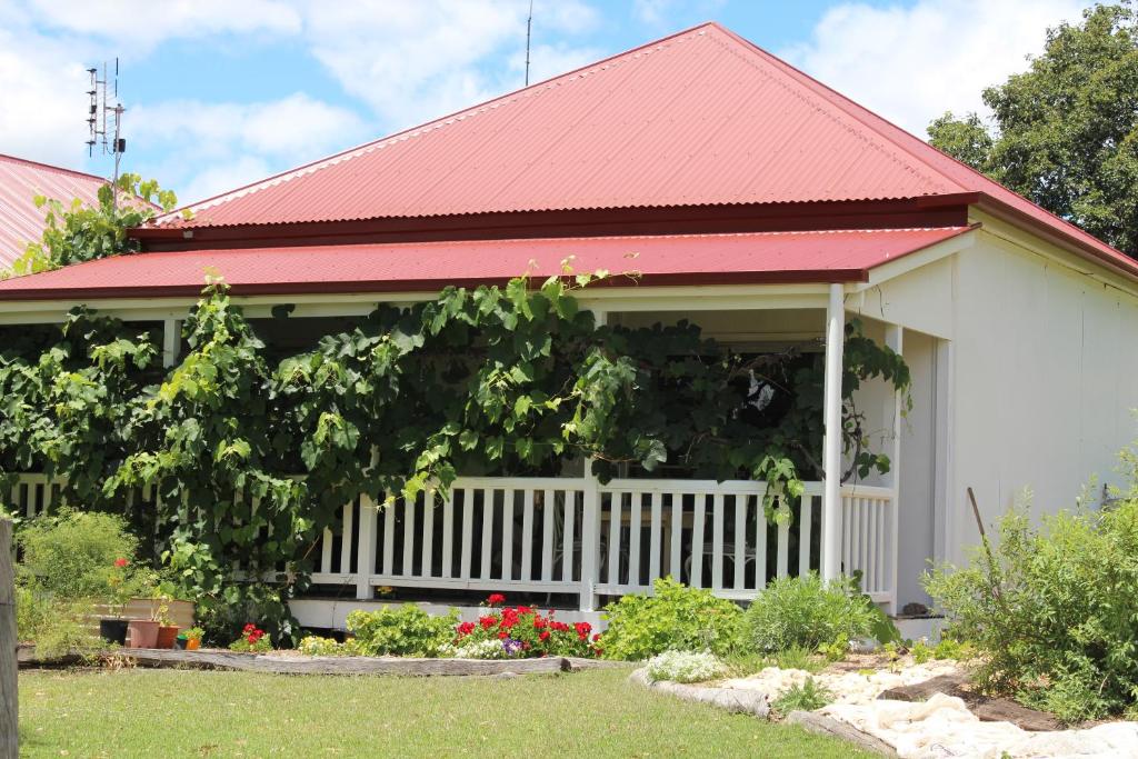 a house with a red roof and a white fence at Glenlyon Dam Holiday Cottage & Farmstay in Stanthorpe