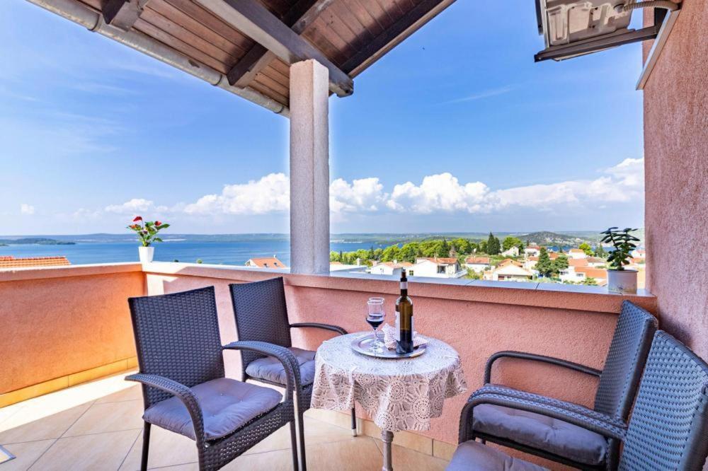 - une table et des chaises sur un balcon avec une bouteille de vin dans l'établissement Apartment ALAN, Sibenik - Bilice, with a sea view, à Šibenik