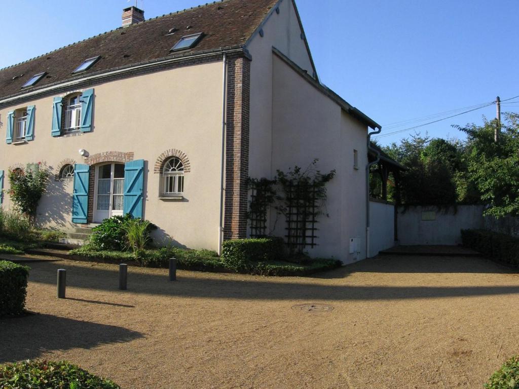 ein weißes Haus mit blauen Fenstern und einer Auffahrt in der Unterkunft Gîte Trizay-Coutretot-Saint-Serge, 4 pièces, 5 personnes - FR-1-581-67 in Trizay-Coutretot-Saint-Serge