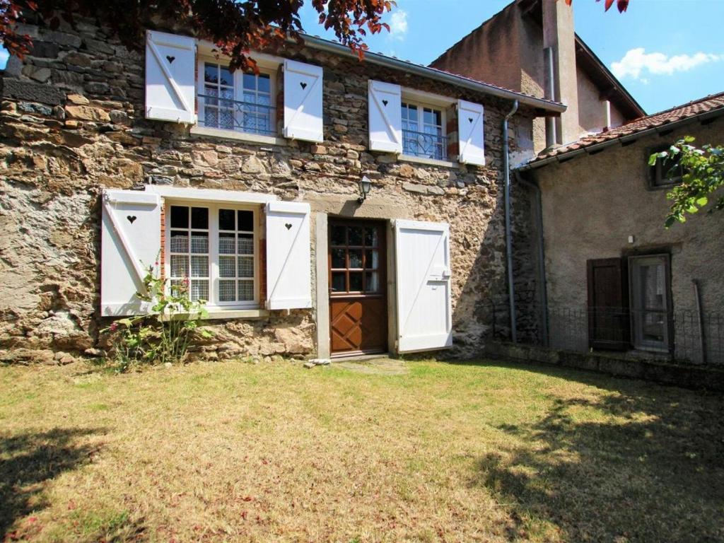 布萊勒的住宿－Gîte Blesle, 3 pièces, 4 personnes - FR-1-582-14，一座带白色门和院子的老石屋