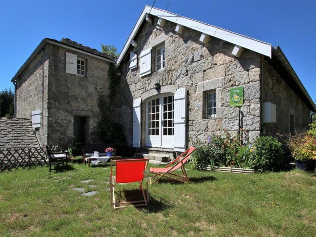 una casa de piedra con una silla roja delante en Gîte Le Chambon-sur-Lignon, 4 pièces, 5 personnes - FR-1-582-137 en Le Chambon-sur-Lignon