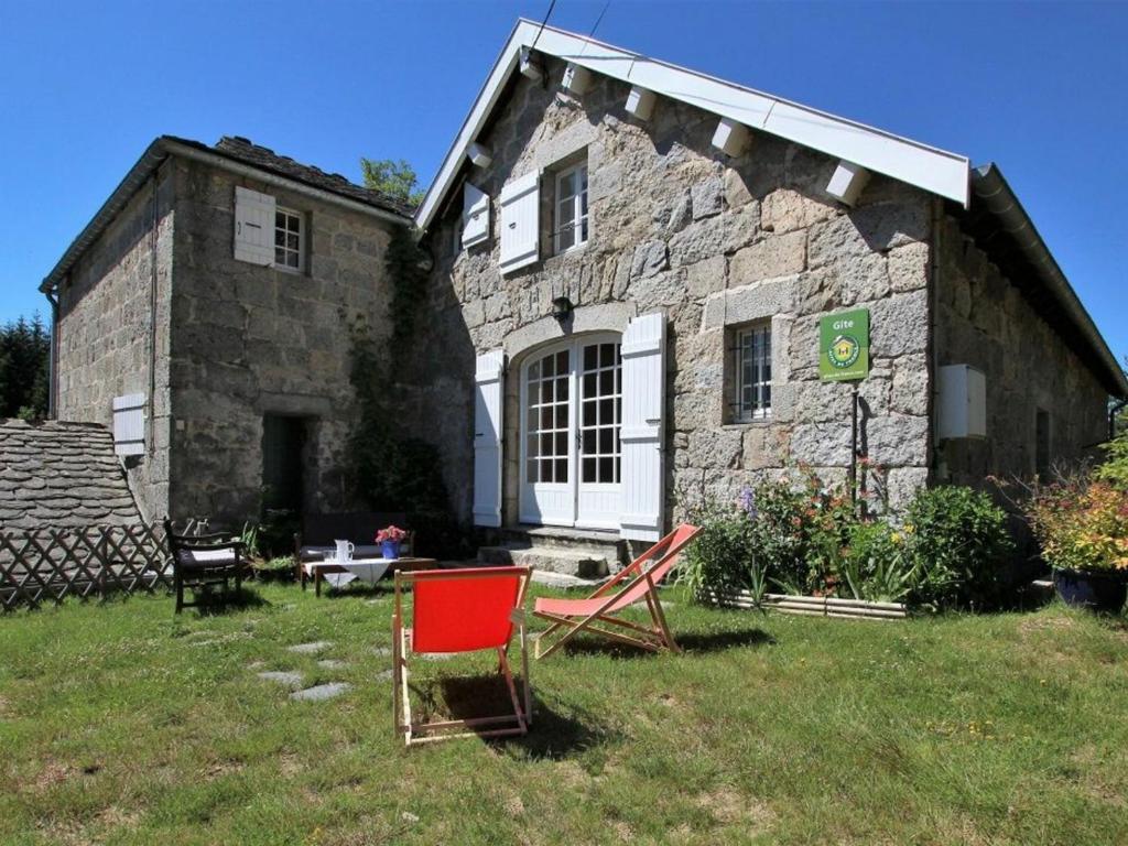 a stone house with a red chair in front of it at Gîte Nature au Chambon-sur-Lignon: Terrasse, Wifi, Proche Activités et Commerces - FR-1-582-137 in Le Chambon-sur-Lignon