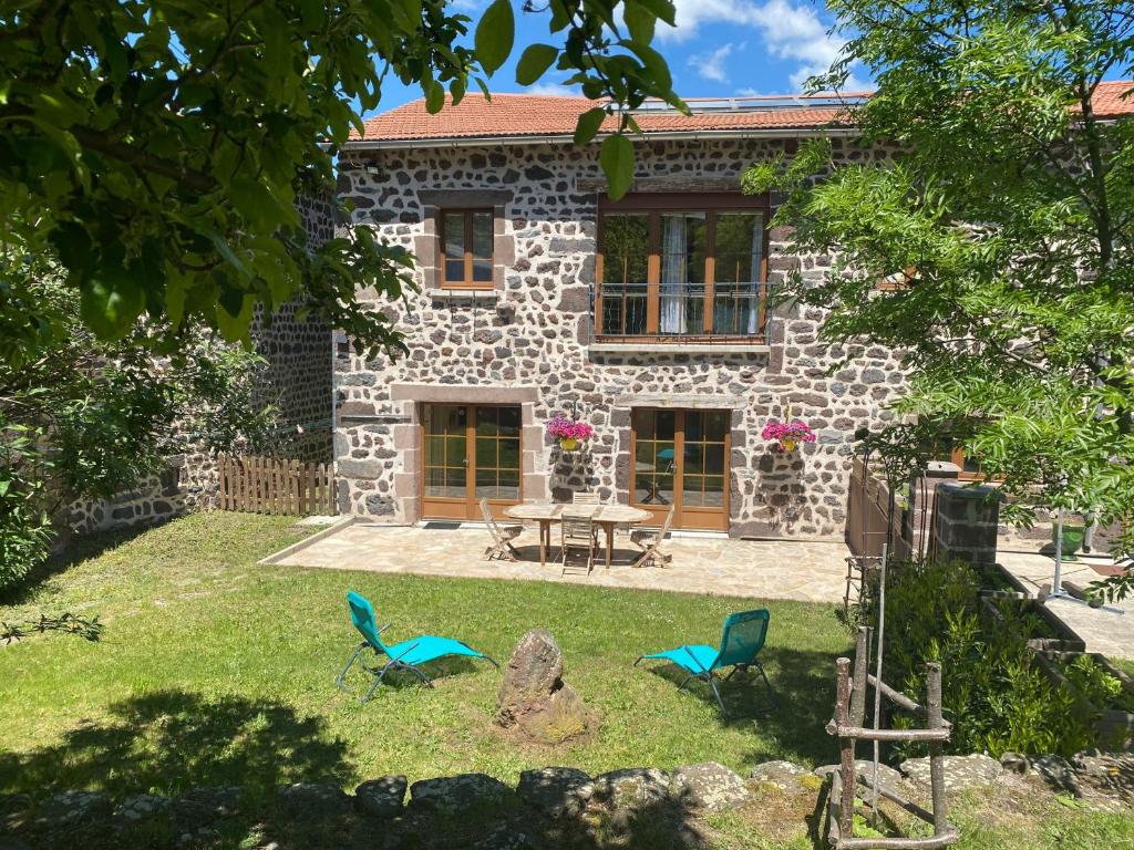 ein Steinhaus mit einem Tisch und Stühlen davor in der Unterkunft Gîte à la ferme à Saint-Christophe-sur-Dolaison avec terrasse et chambres privatives - FR-1-582-284 in Saint-Christophe-sur-Dolaison