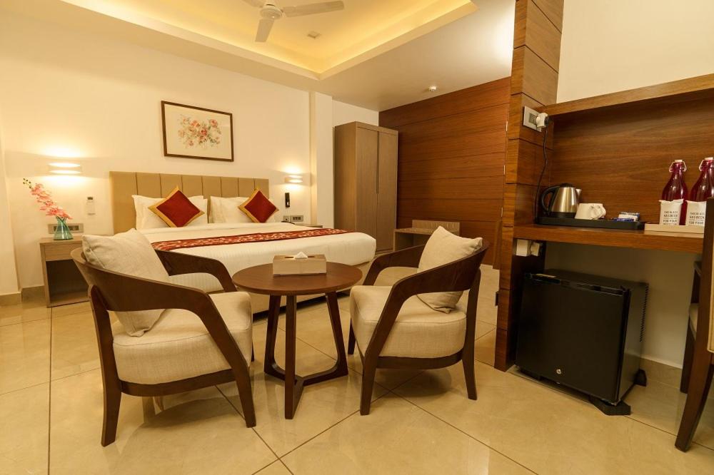 Habitación de hotel con cama, mesa y sillas en Soorya en Attingal