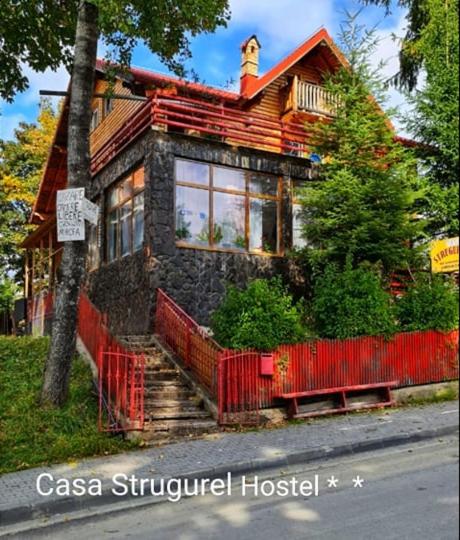 a house with a red fence in front of it at vila strugurelu hostel in Predeal