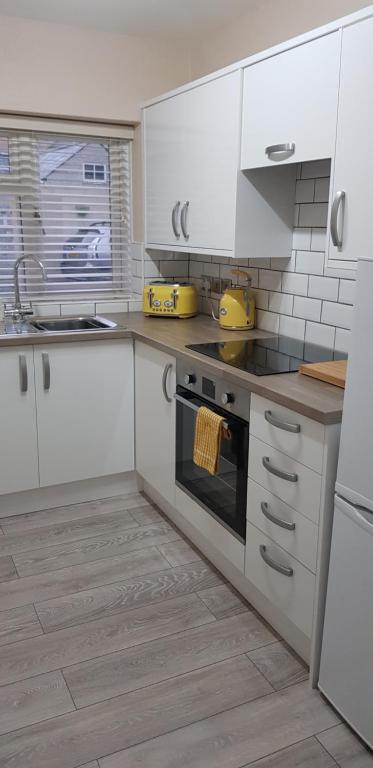 a kitchen with white cabinets and a stove top oven at Chynoweth Court in Newquay