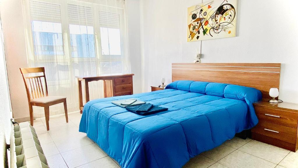 a bedroom with a blue bed and a chair at Hostal Sol Naciente in León
