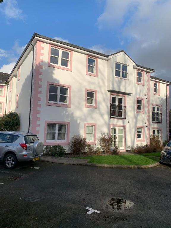凯西克Keswick Ground floor apartment with parking的一栋白色建筑，前面停着一辆汽车