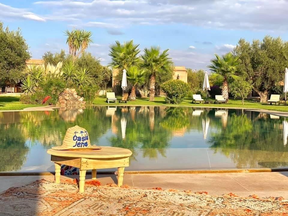 un chapeau assis sur un banc devant un étang dans l'établissement Oasis Jena Marrakech, à Marrakech