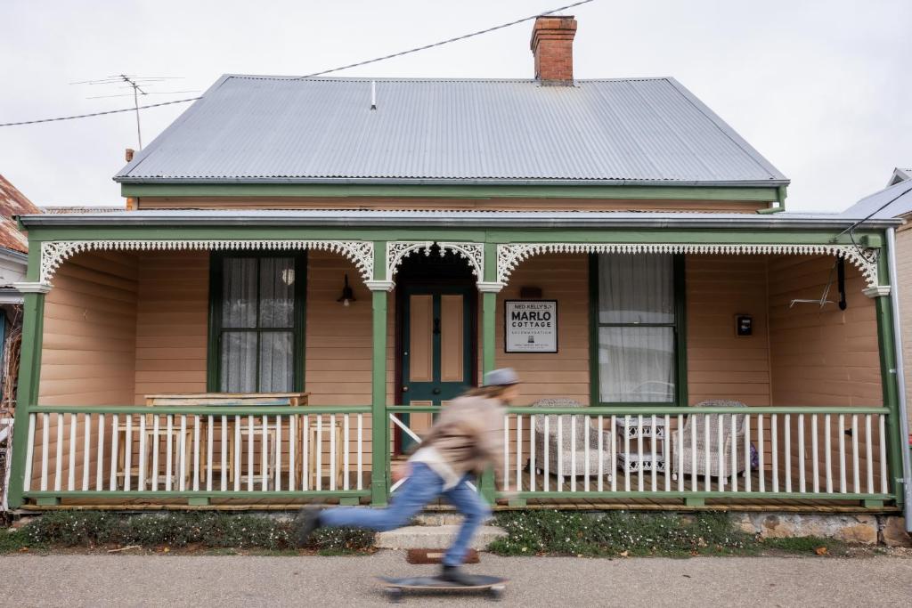 un hombre montando una patineta delante de una casa en Ned Kelly’s Marlo Cottage - in the best Beechworth location, en Beechworth