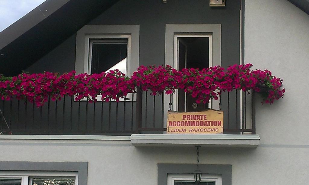 uma varanda com flores cor-de-rosa e um cartaz em Private accommodation Lidija Rakočević em Kolašin