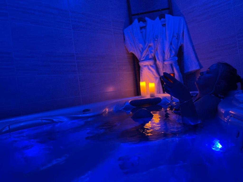 Una mujer está sentada en una bañera con una luz azul en Séjour Romantique Jacuzzi intérieur Privé, en Le Vigan