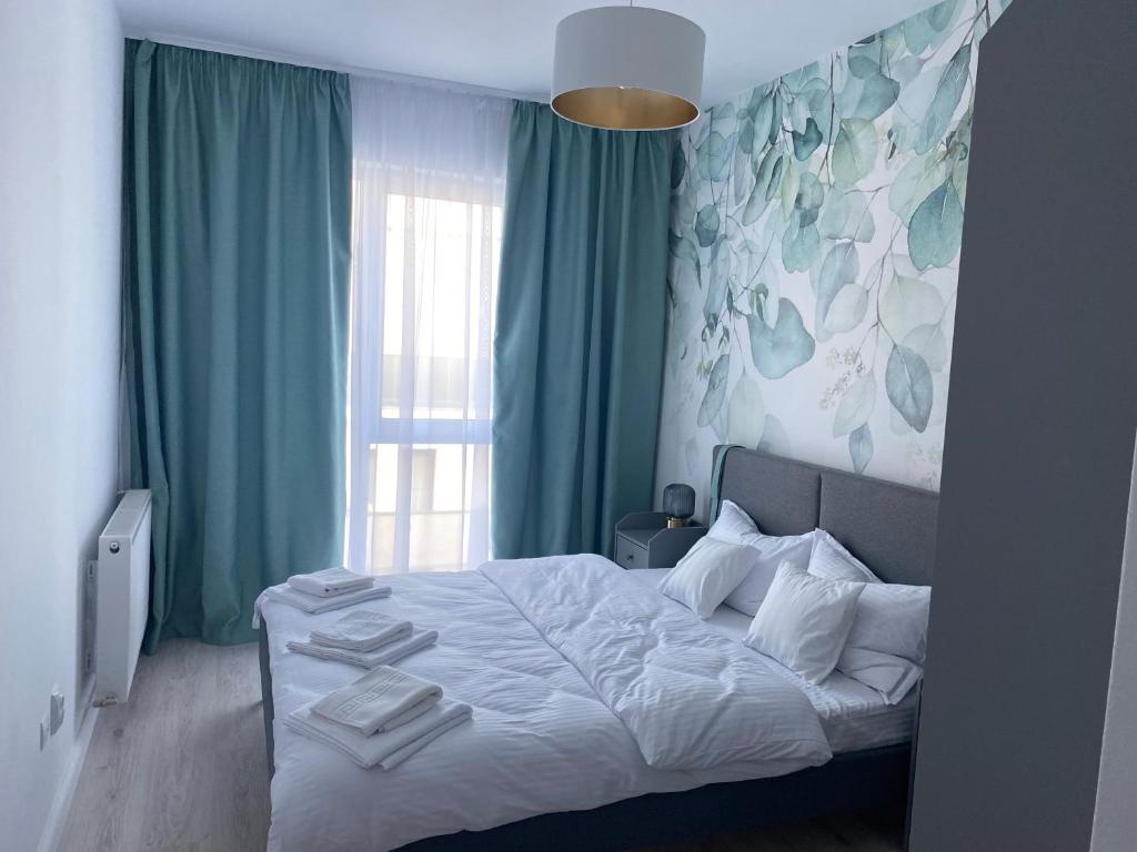 a bedroom with a bed with green curtains and a window at Veles Apartments in Sibiu