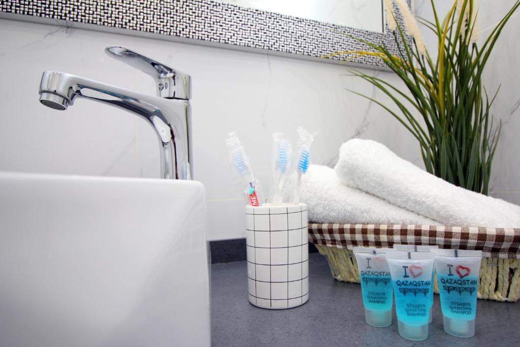 a bathroom with toothbrushes in cups next to a sink at Great Cozy Apt in the heart of the city TU116 in Almaty