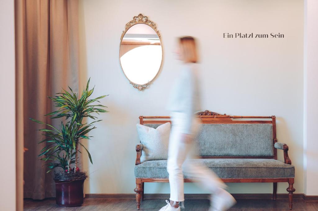 a person walking through a living room with a chair and a mirror at Hotel Gasthaus Post in Campo di Trens