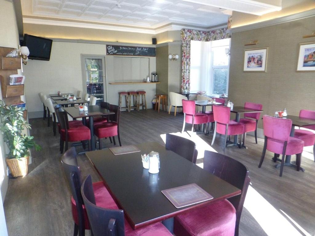 una sala da pranzo con tavoli e sedie rosa di Arrandale House a Douglas