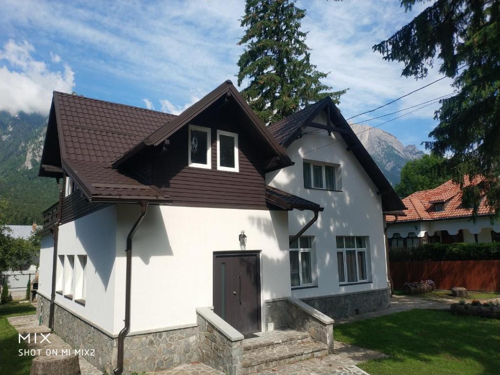 una casa blanca con techo marrón en Vila Panduri 23, en Buşteni