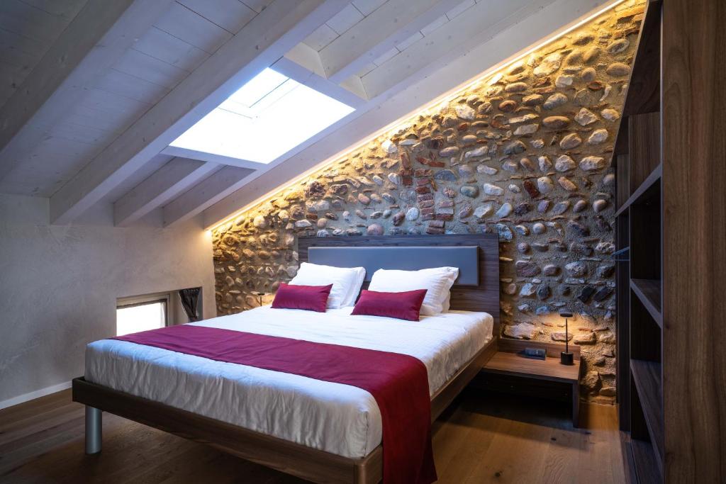 ein Schlafzimmer mit einem großen Bett und einer Steinmauer in der Unterkunft Loft Roby in Peschiera del Garda