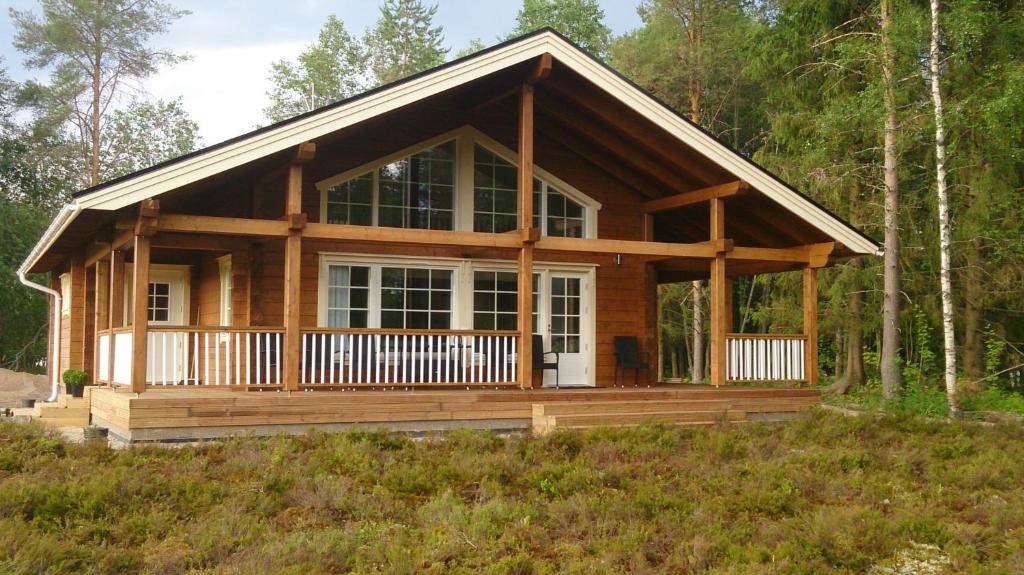 uma cabana de madeira na floresta com um alpendre em Koskikara Cottage em Kymönkoski