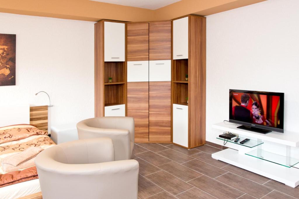 a bedroom with a bed and a tv and chairs at Ferienwohnung Familie Leinweber in Waren