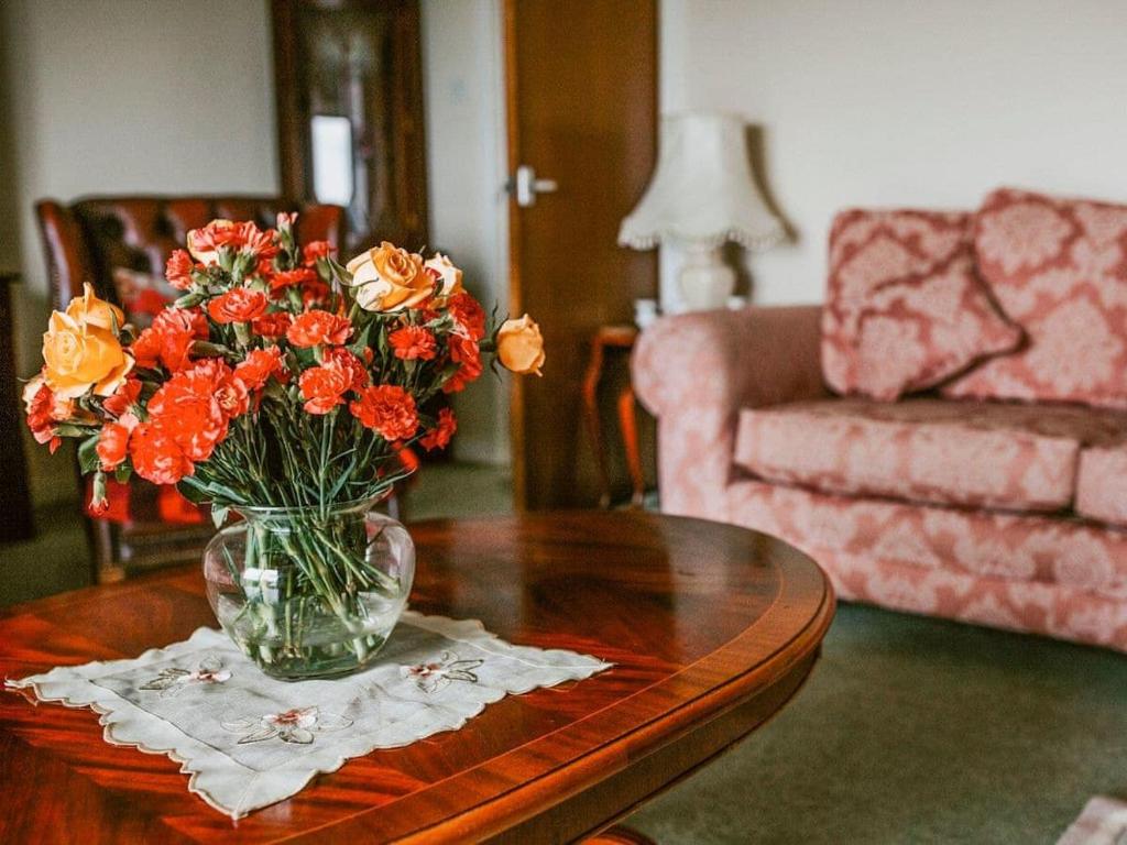 a vase of flowers on a table in a living room at Hollyburn in Breasclete
