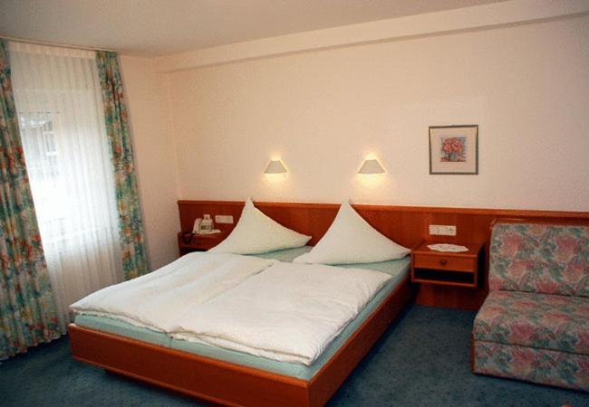 une chambre d'hôtel avec un lit et une chaise dans l'établissement Gasthaus Merkel Hotel, à Bad Berneck im Fichtelgebirge