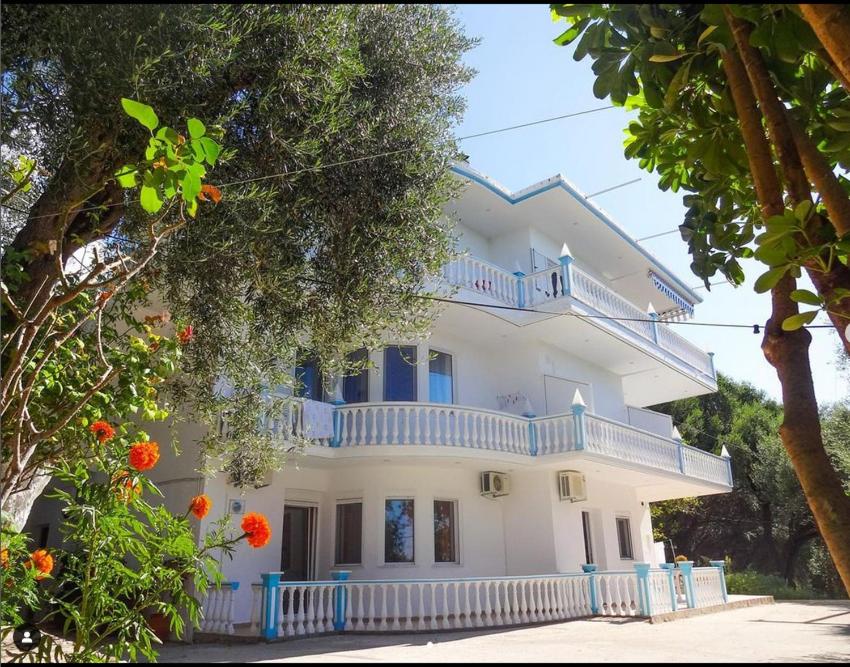 ein großes weißes Haus mit blauen Balkonen und Bäumen in der Unterkunft Angelos Studios in Parga