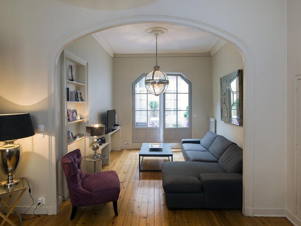 ein Wohnzimmer mit einem Sofa und einem Stuhl in der Unterkunft Bord'ôappart Le Cheverus in Bordeaux