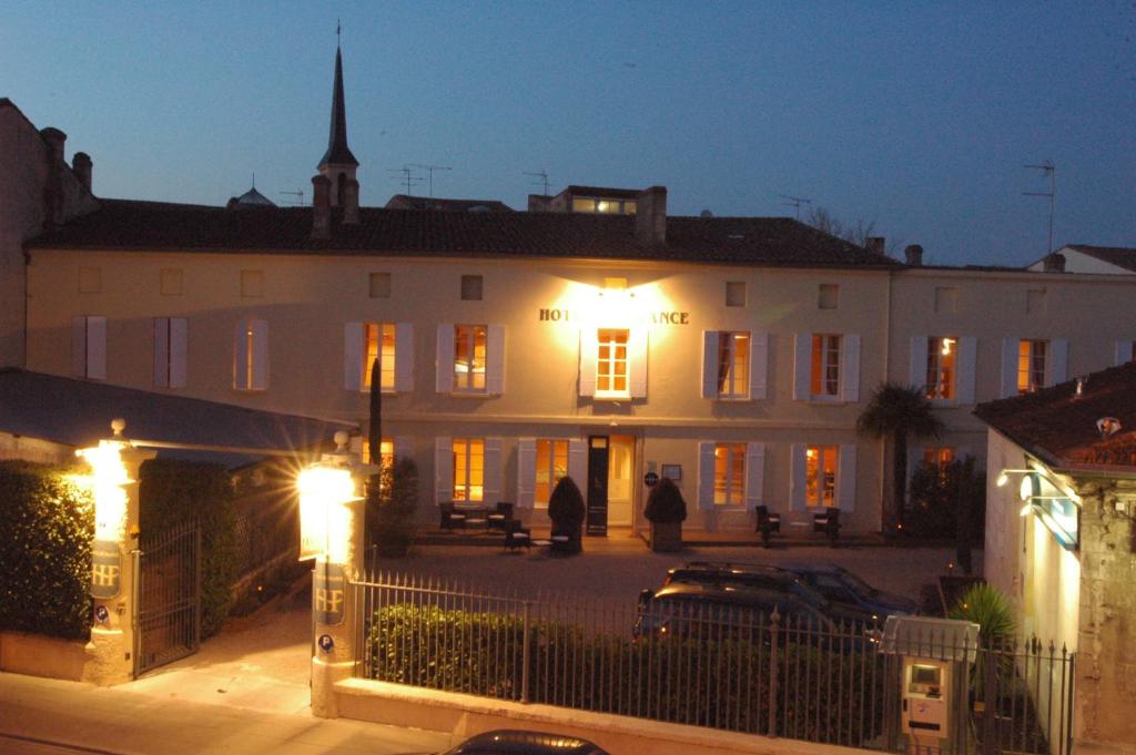 duży biały budynek z oświetleniem przed nim w obiekcie Hôtel de France w mieście Libourne