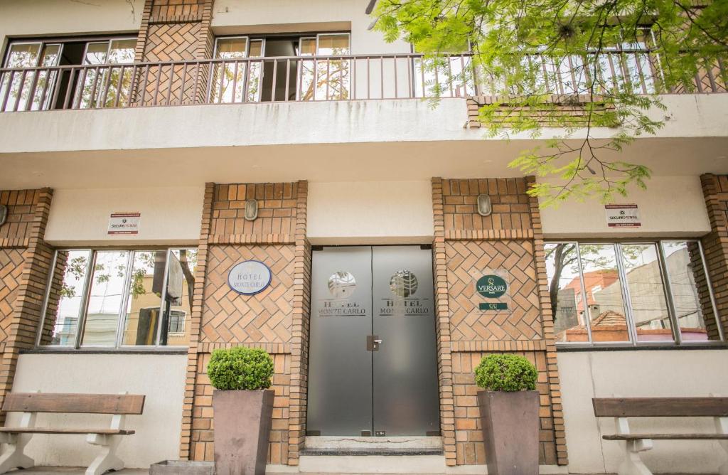 un edificio con una puerta y dos bancos en Hotel Monte Carlo, en Uruguaiana