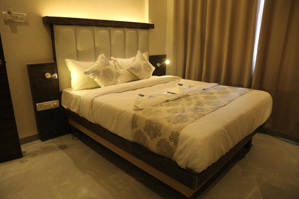 a bedroom with a large bed with white sheets and pillows at Hotel Galaxy Inn in Navi Mumbai