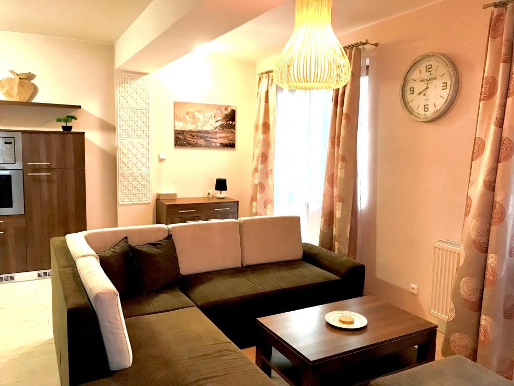 a living room with a couch and a clock on the wall at FeEl Tatras Direct View apartment in Veľká Lomnica