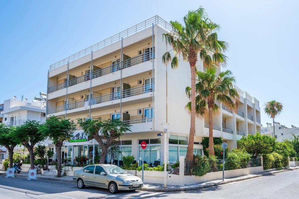 a car parked in front of a building with palm trees at Hotel Koala in Kos