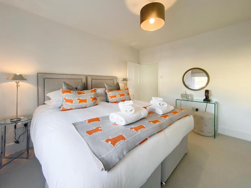 een slaapkamer met een groot wit bed met oranje kussens bij 3 Chestnut Terrace, Long Melford in Long Melford