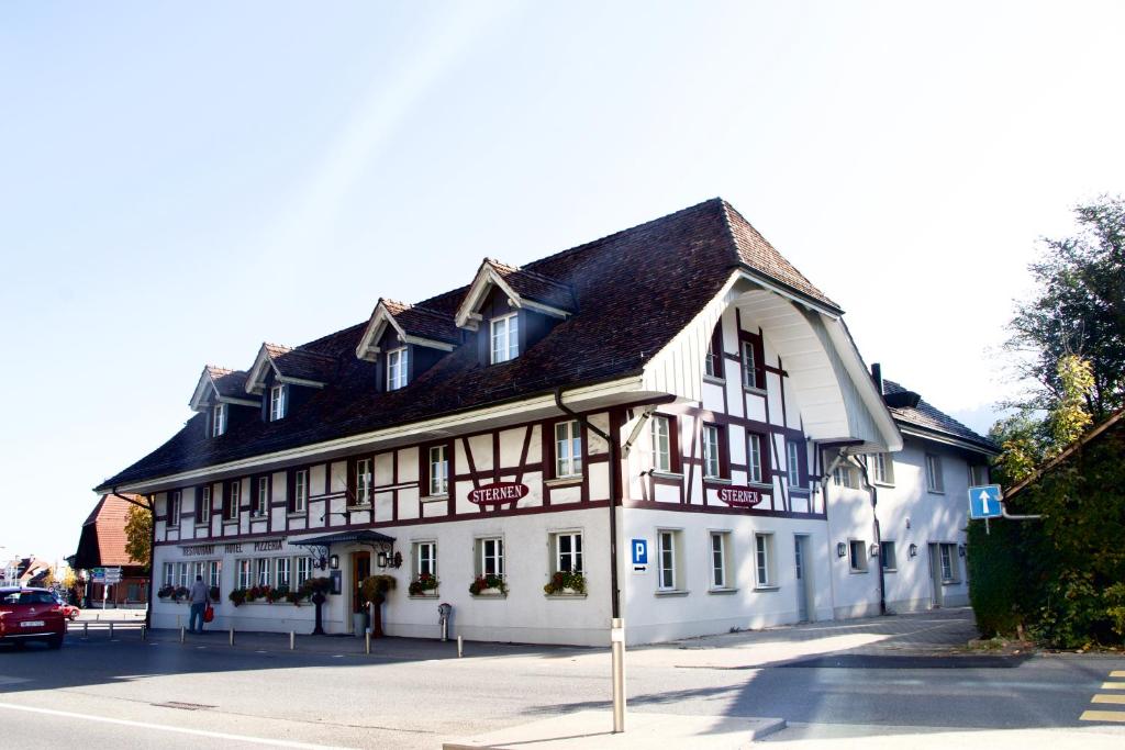 un bâtiment blanc avec un toit noir dans une rue dans l'établissement Hotel & Restaurant Sternen Köniz bei Bern, à Berne