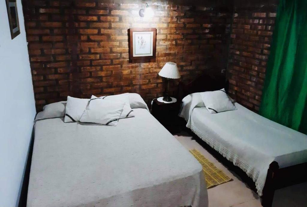 - une chambre avec 2 lits et un mur en briques dans l'établissement Estancia San Carlos, à Luan Toro