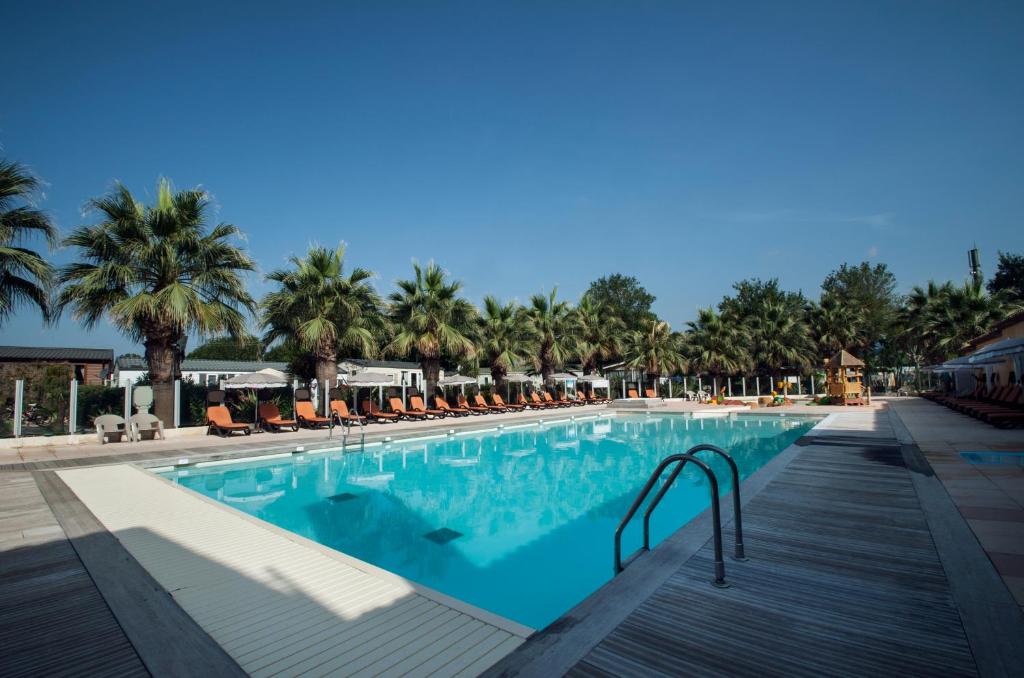 une grande piscine avec chaises et palmiers dans l'établissement Holiday Marina Resort, à Grimaud
