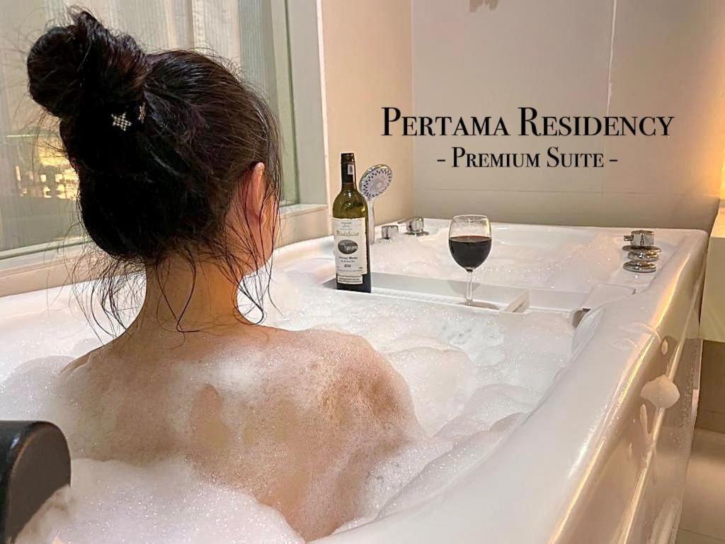a woman sitting in a bath tub with a bottle of wine at Private Jacuzzi Staycation at KL City 152 in Kuala Lumpur