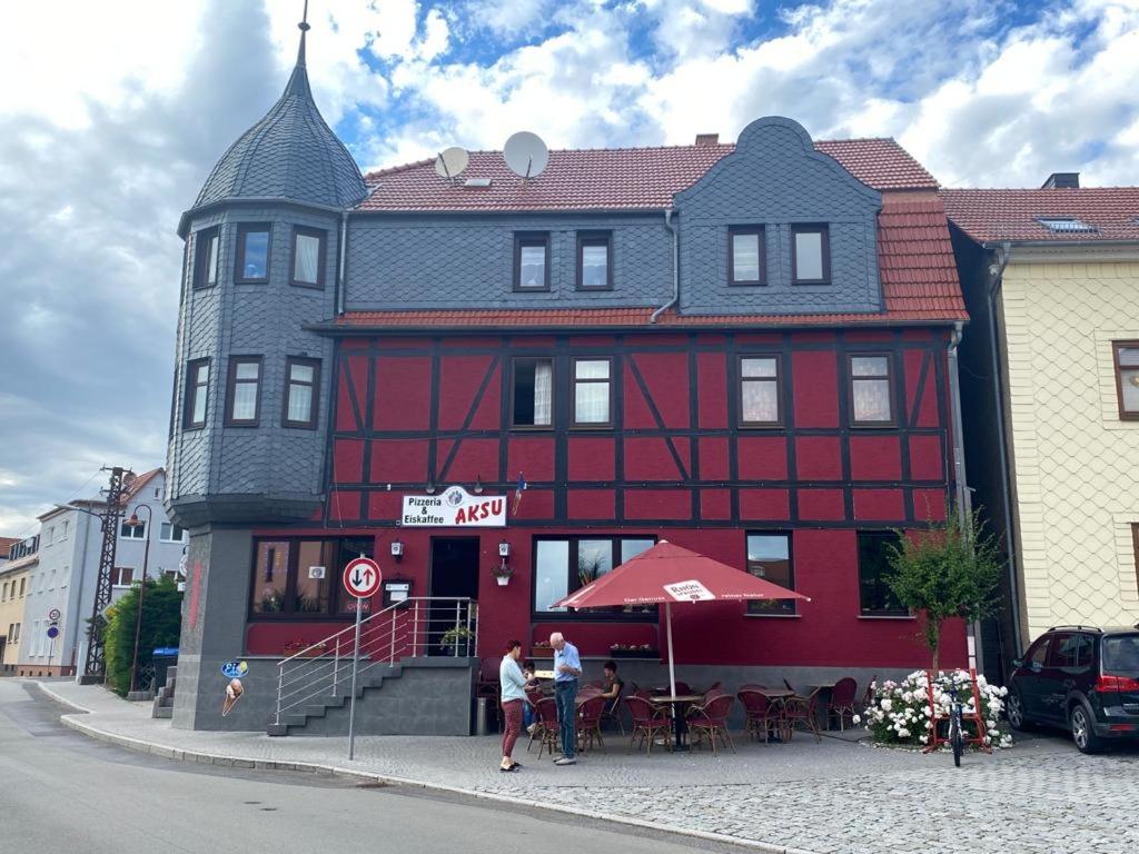 un edificio rojo con gente parada frente a él en Ferienwohnung in der schönen Rhön en Stadtlengsfeld