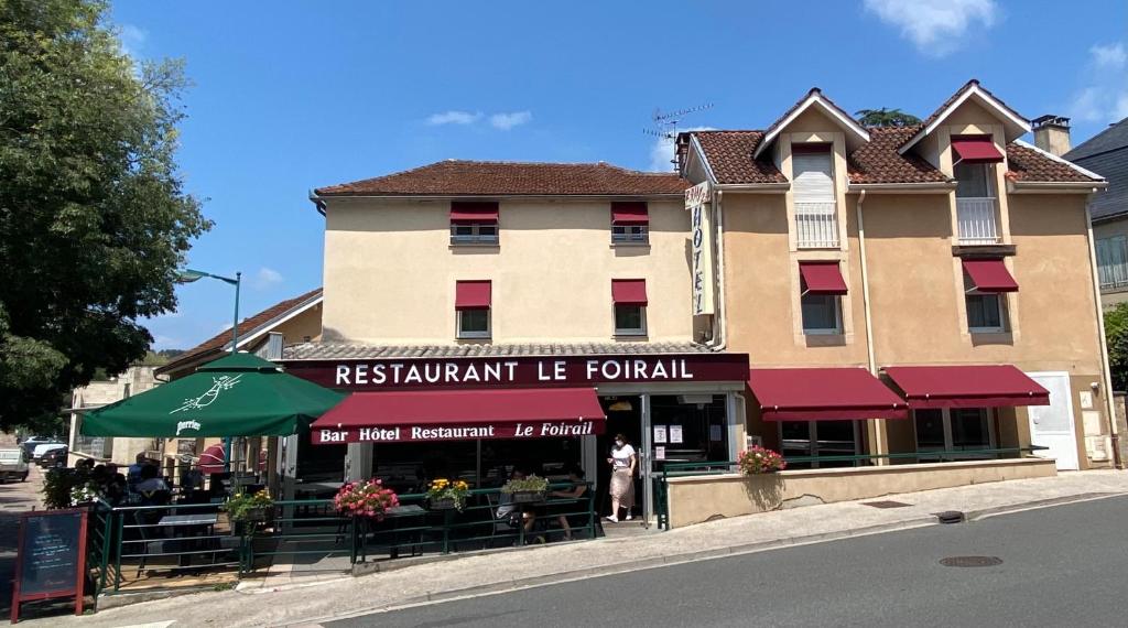restauracja z zielonym parasolem przed budynkiem w obiekcie HOTEL LE FOIRAIL w mieście Figeac