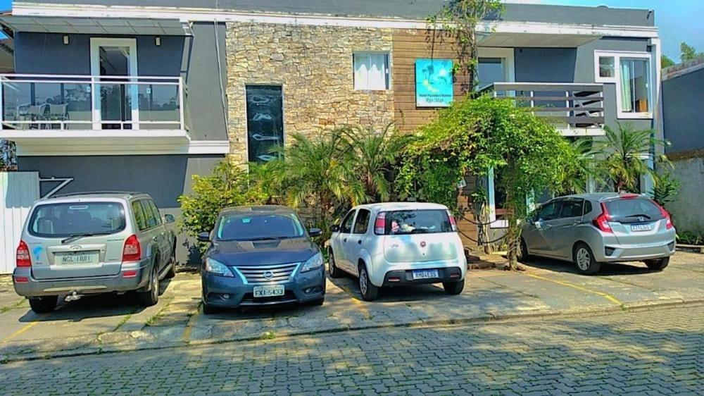 three cars parked in a parking lot in front of a house at Hotel Pousada Rio Mar in Ubatuba