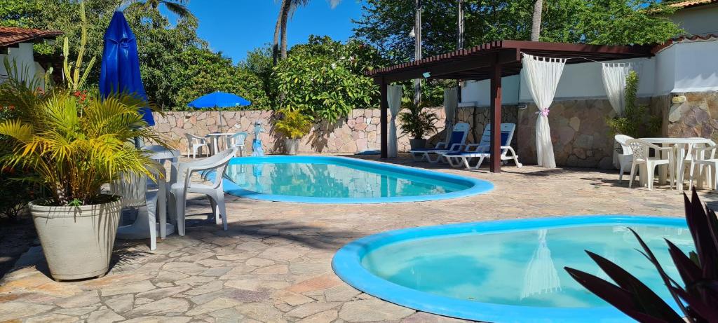 a swimming pool in a yard with chairs and a table at Pousada das Oliveiras in Porto De Galinhas