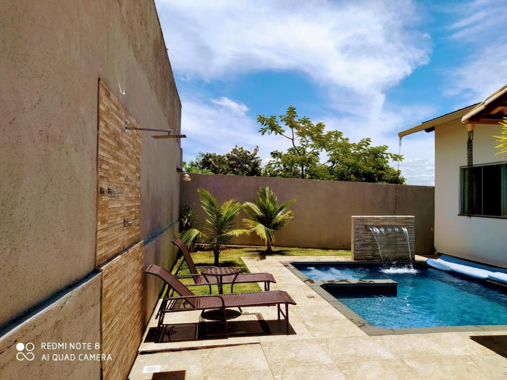 um quintal com piscina e cadeiras ao lado de um edifício em Casa de campo com piscina aquecida por sistema solar em Lagoa Santa
