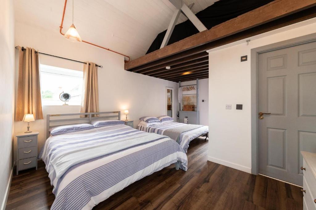 a bedroom with two beds and a door at Coastguard Boat House on Belfast Lough in Newtownabbey