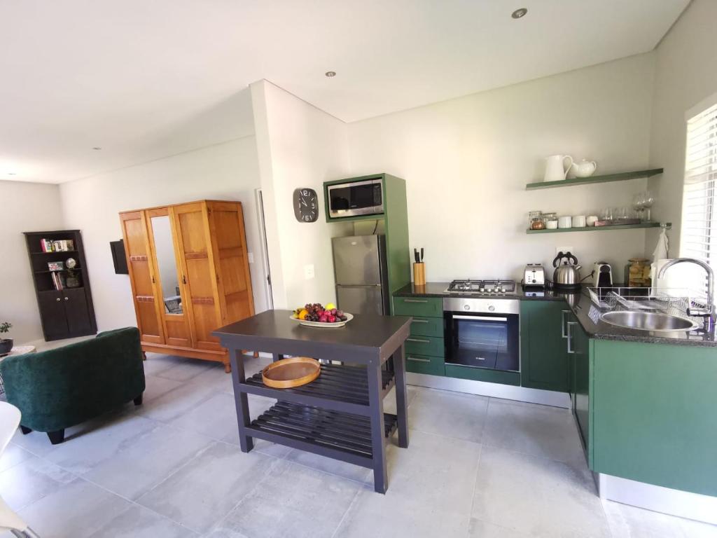 eine Küche mit grünen Schränken und einem Tisch mit einer Schale Obst in der Unterkunft Oak Village in Stellenbosch